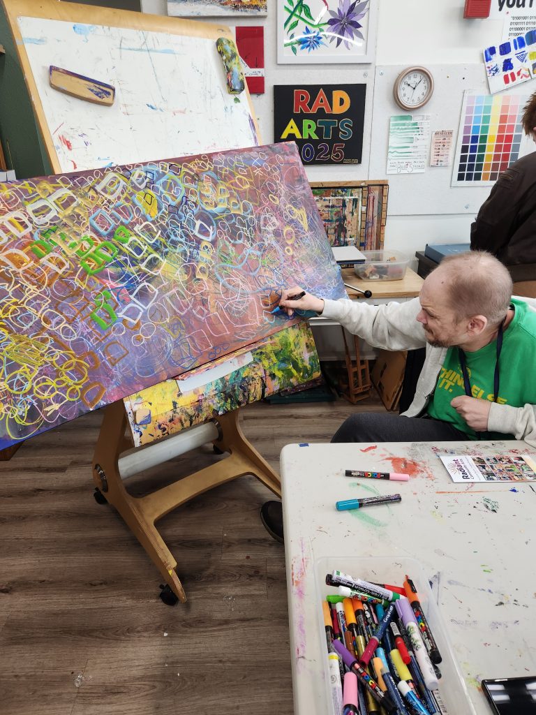 Richard Pierce uses an adaptive easel to work on his abstract painting in the Radiant Community Arts art studio